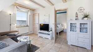 Un salon comprenant un canapé, un téléviseur et un meuble avec des portes en verre.