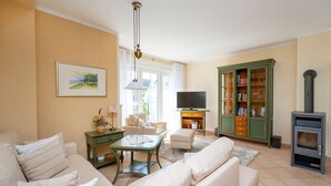 Ein Wohnzimmer mit einer Couch, einem Couchtisch, einem Fernseher, einem Bücherregal und einem Kamin.