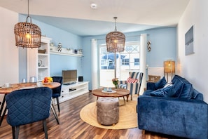 A living room with a blue couch, a round coffee table, a TV, and wicker lamps.