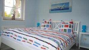 Une chambre à coucher avec un lit, une fenêtre, un tableau et une table de chevet.