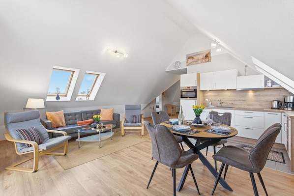 A modern loft apartment with a dining area, kitchen, and seating space.