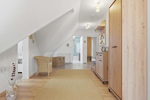 A spacious loft bedroom with a sloped ceiling, a large wardrobe, and a view of the living area.