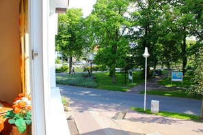 A view from a window overlooking a street lined with trees and a sidewalk.