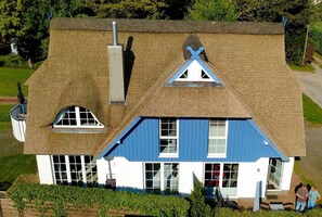 Ein zweistöckiges Haus mit einem steilen Dach, einem Schornstein und einer blauen und weißen Fassade.