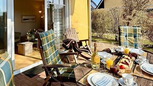 Un espace extérieur aménagé pour prendre les repas, avec des chaises en osier et une table dressée pour le petit-déjeuner.
