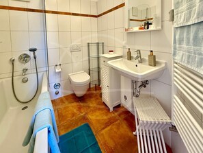 Une salle de bain équipée d’une baignoire, de toilettes, d’un lavabo et d’un porte-serviettes.
