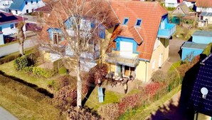 Un quartier résidentiel avec des maisons, un arbre et un ciel dégagé.