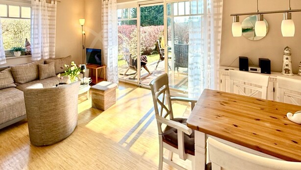 Un salon moderne avec un canapé, une table à manger en bois et un téléviseur.