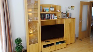 Una sala de estar con un mueble de madera para entretenimiento, un televisor de pantalla plana y una vitrina de vidrio con copas de vino.