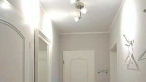 Ein Korridor mit Holzboden, weißen Wänden, einer weißen Tür und einer Deckenleuchte.