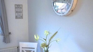 Ein Essbereich mit einem Holztisch, einer Blumenvase, einer Uhr und einem Schild an der Wand.
