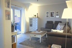Ett vardagsrum med en soffa, ett soffbord, ett skåp och en lampa.