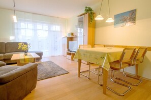 Ein modernes Wohnzimmer mit einer Couch, einem Couchtisch und einem Essbereich mit Tisch und Stühlen.