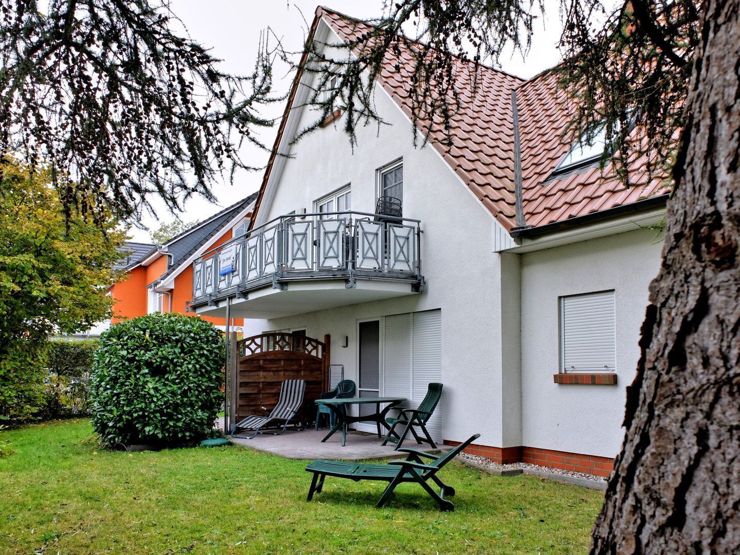 A house with a balcony, a patio with outdoor furniture, and a well-maintained lawn.