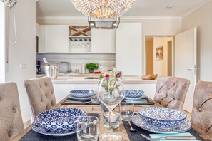 A dining area with a table set for four, featuring blue and white patterned plates, clear glassware, and a decorative vase with flowers.