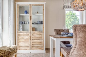 A dining area with a wooden cabinet, a table with chairs, and a view of the outdoors.