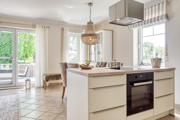 A modern kitchen with a central island, a built-in oven, and a pendant light.