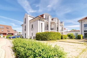 Ein modernes Mehrfamilienhaus mit Balkonen und einer gepflasterten Auffahrt.
