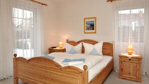 A wooden bed with a headboard, two bedside tables with lamps, and a framed picture on the wall.