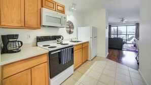 Una cocina con armarios de madera, microondas, estufa y refrigerador.