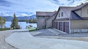 Una casa moderna de dos pisos con garaje, entrada para vehículos y vista al lago.