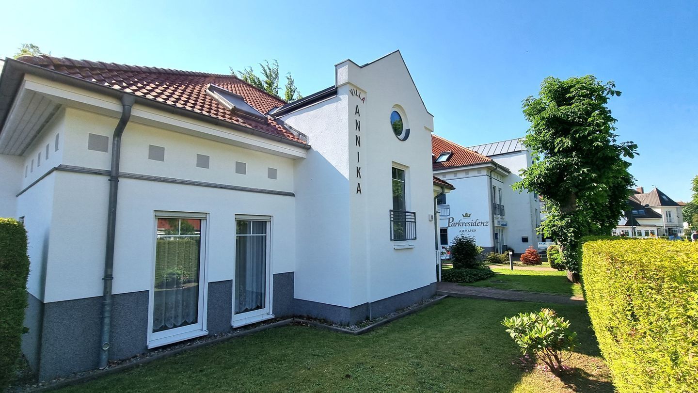 A white building with a red-tiled roof, a small garden, and a sign that reads "Parkresidenz."