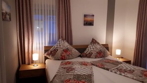 A neatly made bed with floral-patterned bedding, two bedside lamps, and a nightstand.
