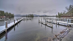 Un lac paisible, avec des quais qui s’avancent dans l’eau, entouré d’arbres et bordé de montagnes au loin.