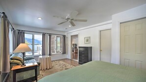 Une chambre à coucher comprenant un lit, une table de chevet, une lampe, une commode et une vue sur l’extérieur.