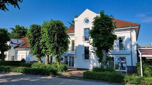 Ein weißes Gebäude mit rotem Ziegeldach, umgeben von viel Grün.