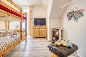 A compact room with bunk beds, a television, a bookshelf, and a butterfly wall art. - Comfortable vacation apartment with balcony near the beach and center in Zingst - (Zingst)