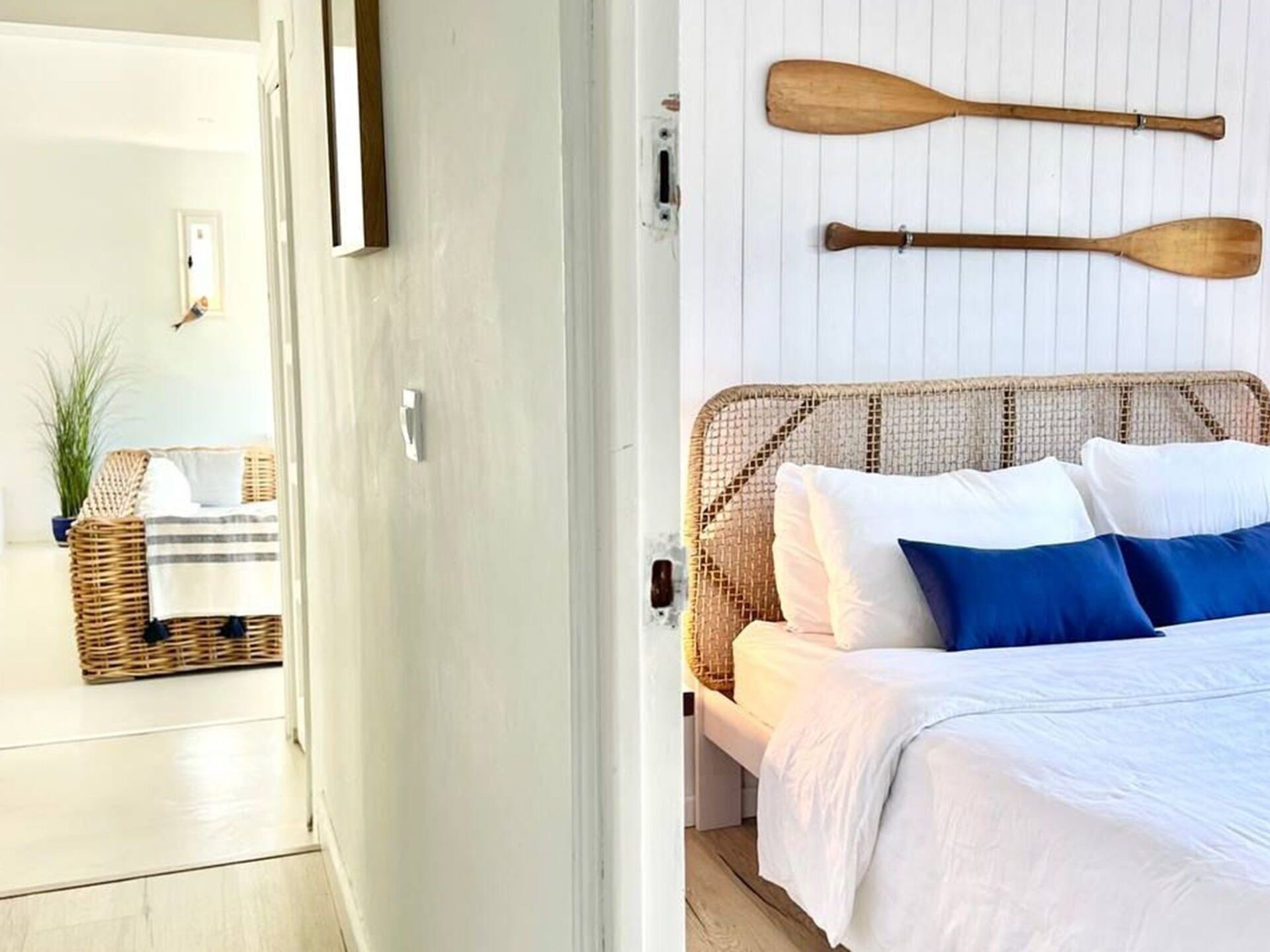 A bedroom with a bed, a wicker headboard, and two wooden paddles on the wall.