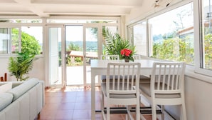 A bright room with a dining table, chairs, a sofa, and a view through large windows. - Wonderful private villa for 10 guests with private pool, WIFI, A/C, TV, patio and panoramic view (Calonge)
