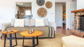 A living room with a sofa, two round tables, a fireplace, and wall decor. - Wonderful private villa for 10 guests with private pool, WIFI, A/C, TV, patio and panoramic view (Calonge)