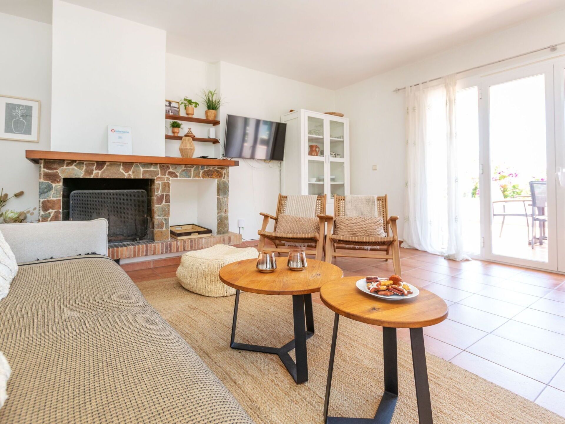 A living room with a stone fireplace, a sofa, two armchairs, a coffee table, and a dining table with food.