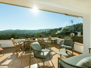 Um terraço com mesa e cadeiras, vista para o campo e uma antena parabólica.