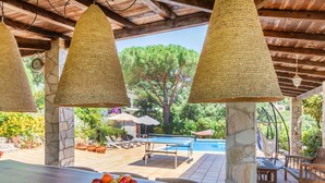 A poolside area with wicker lamps, a stone pillar, and a bowl of fruit on a table. - Wonderful private villa for 10 guests with private pool, WIFI, A/C, TV, patio and panoramic view (Calonge)