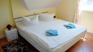 A neatly made bed with white linens and two folded blue towels, a bedside table with a lamp, and a patterned rug on the floor. - Comfortable apartment with balcony and modern furnishings in the Baltic Sea resort of Zingst (Zingst)