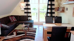 A living room with a sofa, coffee table, and a dining area with a table and chairs. - Comfortable apartment with balcony and modern furnishings in the Baltic Sea resort of Zingst (Zingst)