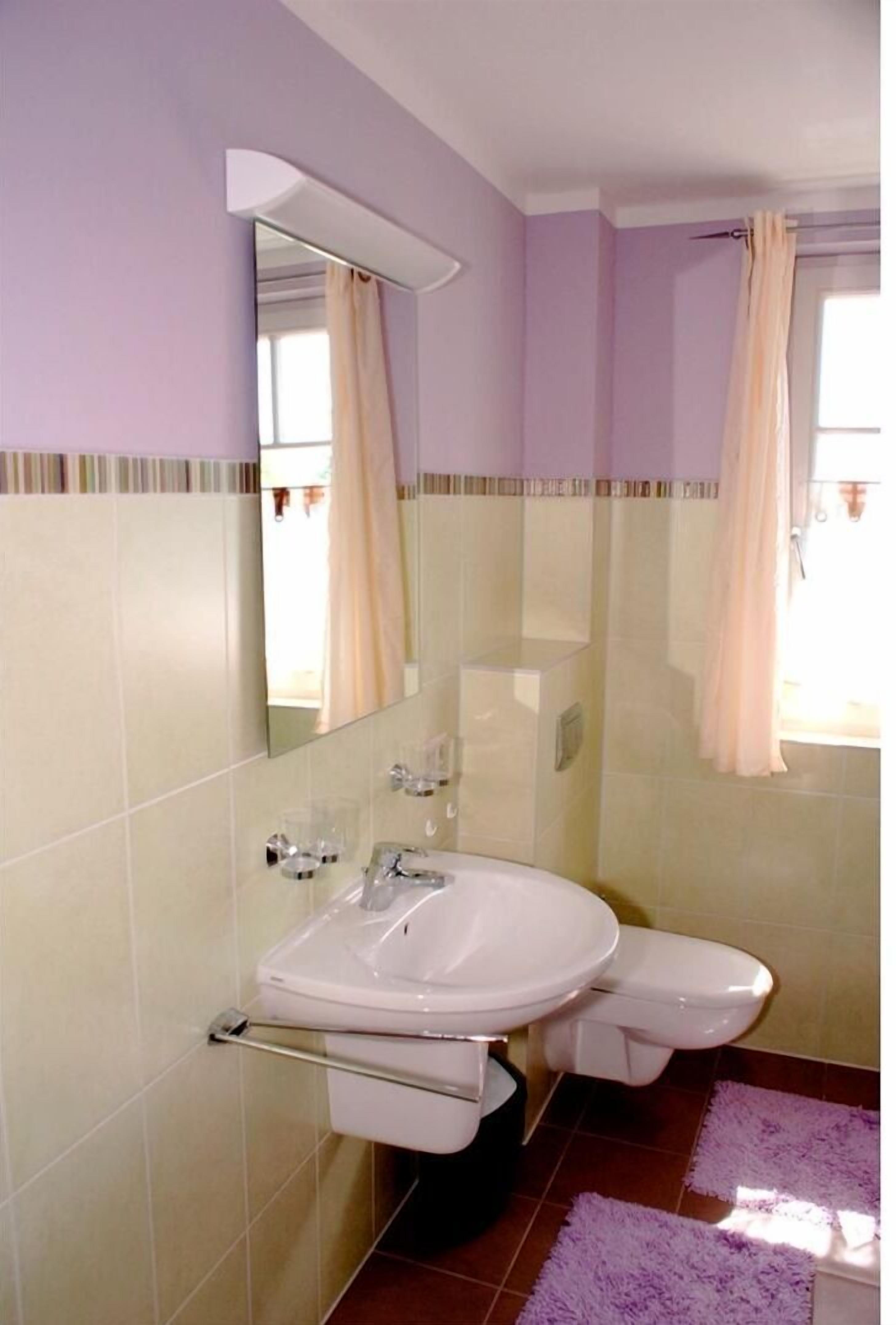 Un baño con lavamanos blanco, un espejo y un inodoro.