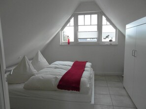 Un dormitorio con cama, ventana y armario.