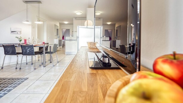 A modern kitchen with a wooden countertop, a built-in oven, and a coffee machine.