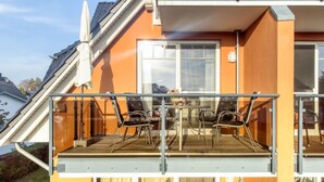 A balcony with two chairs and a table, a window, and a door.
