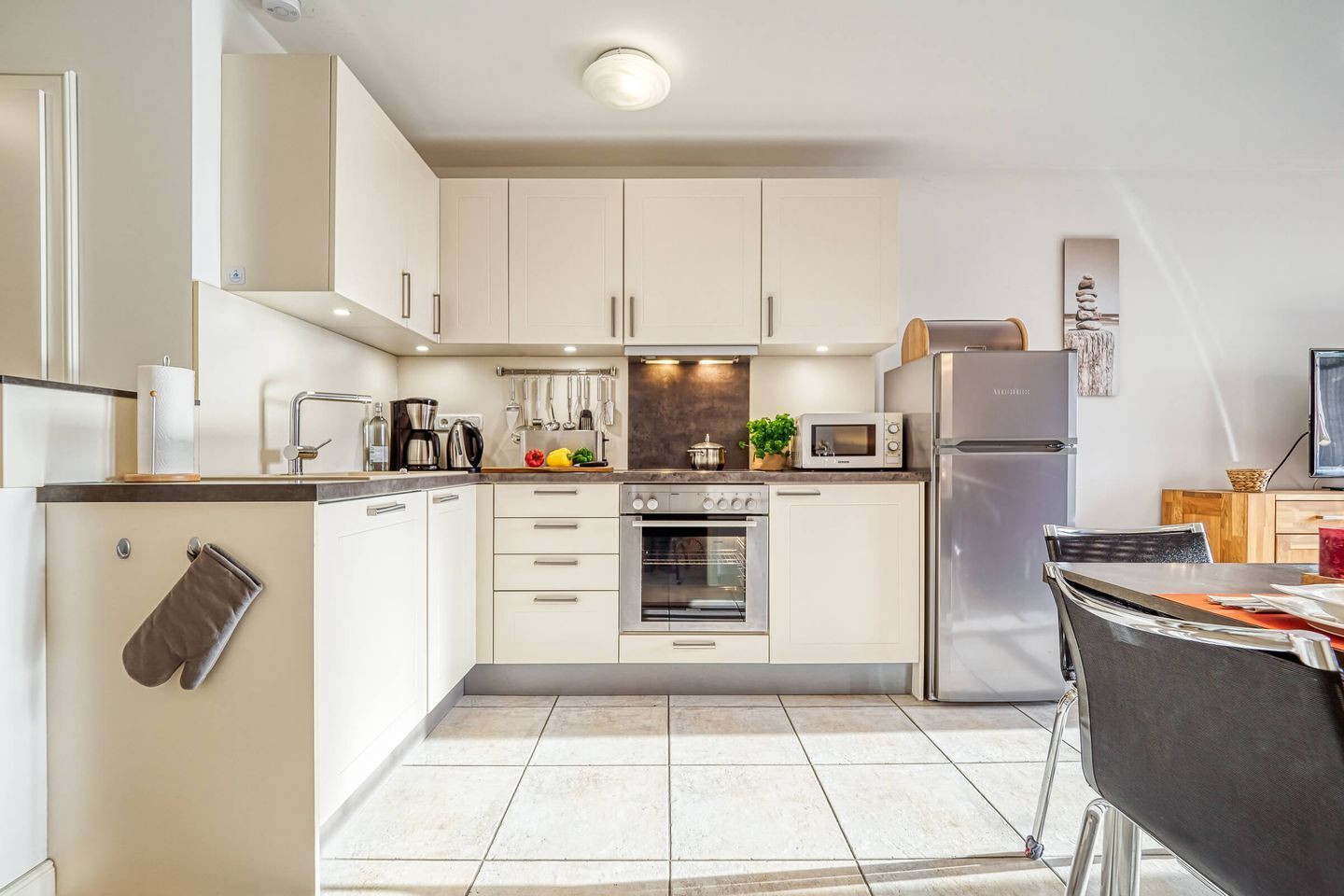 A modern kitchen with white cabinets, a built-in oven, a microwave, and a refrigerator.