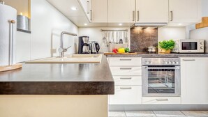 A modern kitchen with white cabinetry, stainless steel appliances, and a central island.