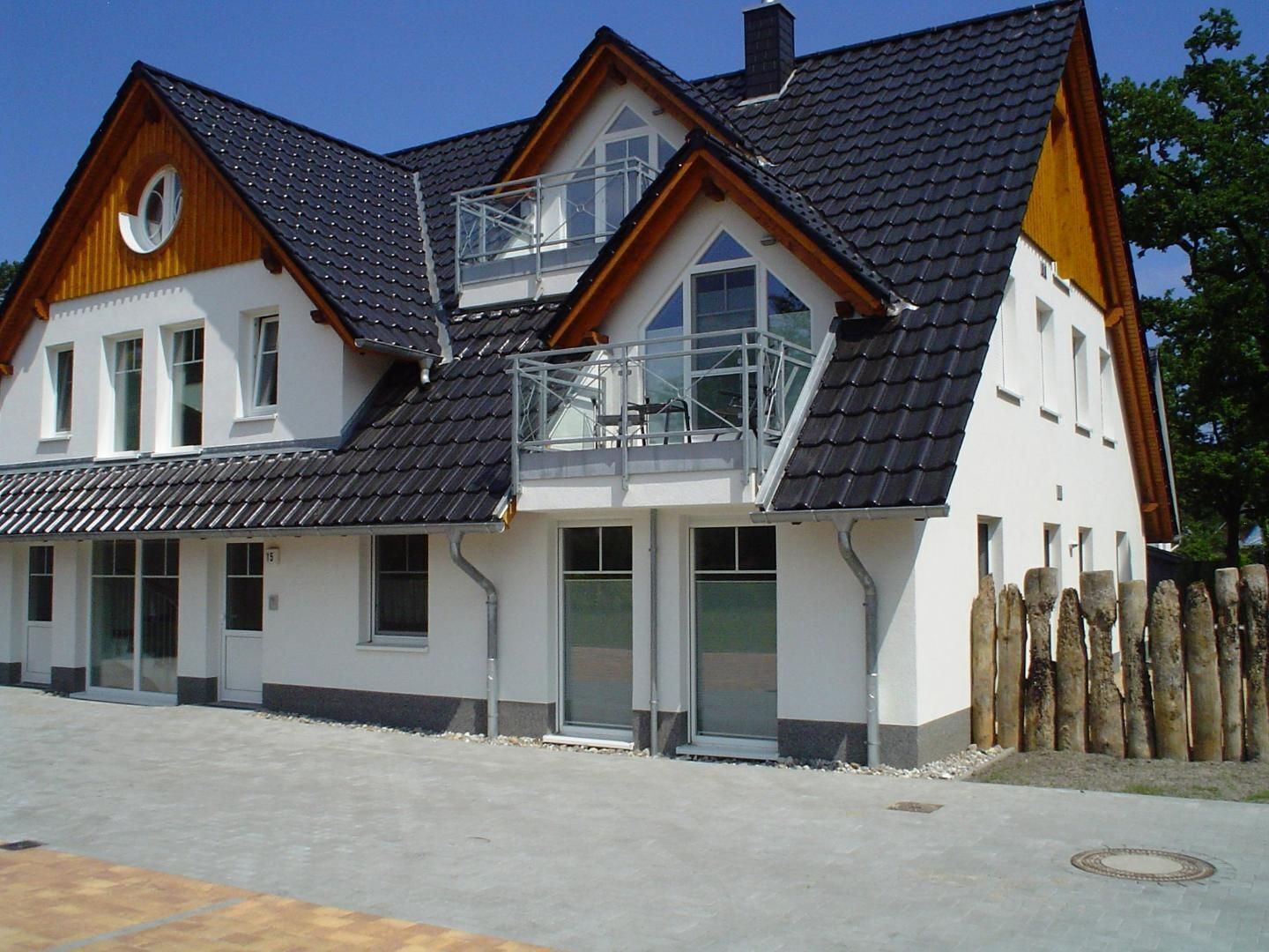 A two-story house with a sloped roof, large windows, and a balcony.