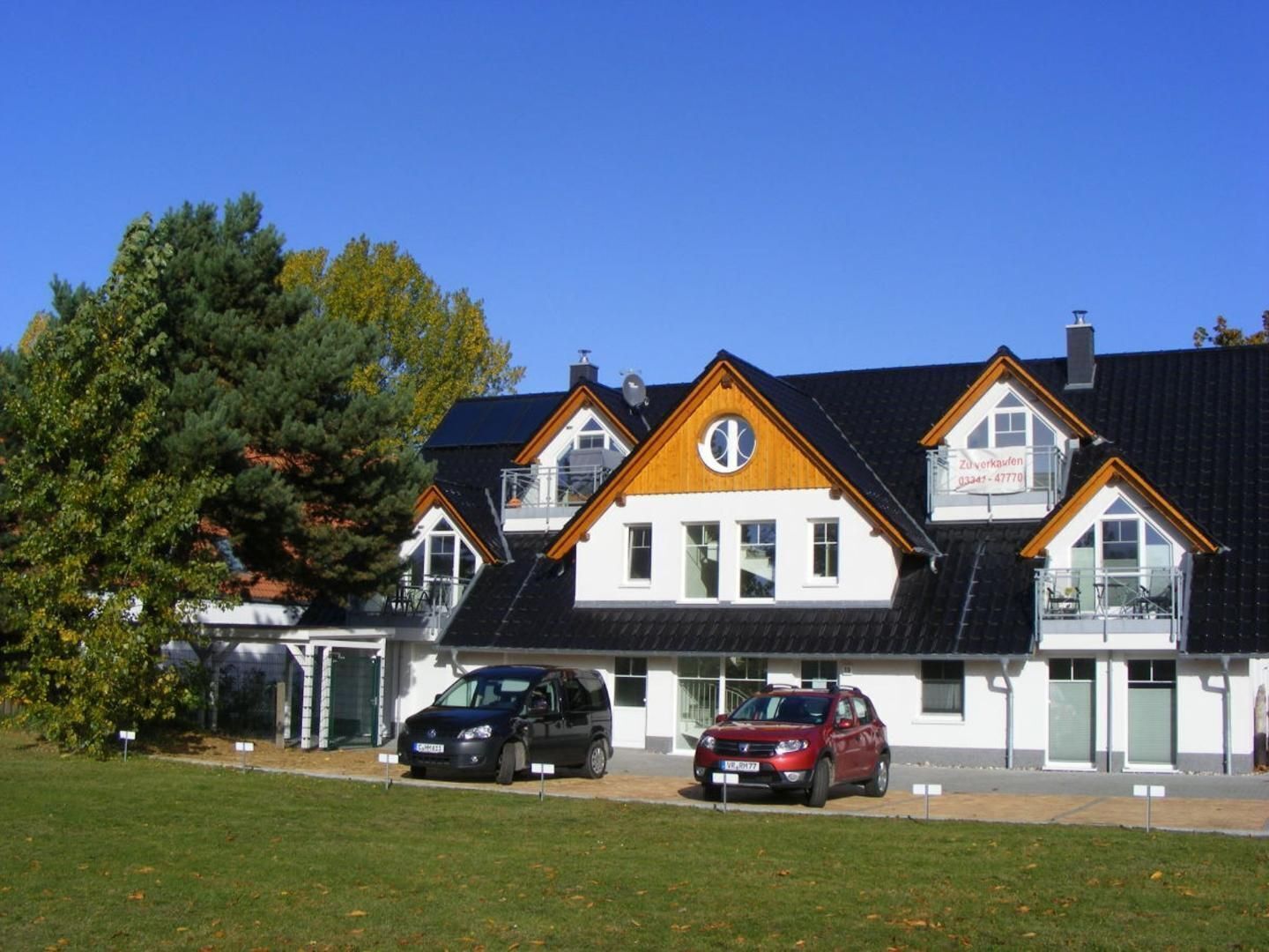 A two-story building with a white facade and dark roof, featuring a prominent circular window on the second floor.