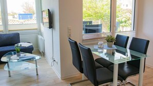 A modern dining area with a glass table, black chairs, and a small potted plant.