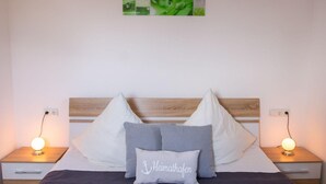 A neatly made bed with a headboard, two bedside tables with lamps, and a wall art piece above the bed.