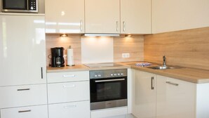 A modern kitchen with white cabinets, a Bosch oven, a microwave, and a coffee maker.